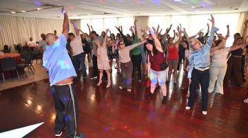 pessoas em pé fazendo movimento de dança. #paratodosverem 