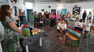 pátio de escola com crianças e adultos em pé para evento solene. #paratodosverem