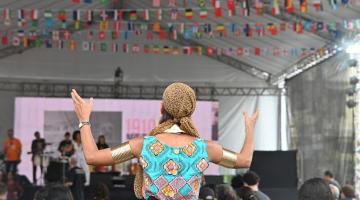 pessoa em pé, de costas para um palco #paratodosverem