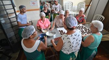 pessoas reunidas em torno de mesa fazendo bombons. #paratodosverem