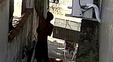 homem está de costas trepado em muro de unidade de saúde. #paratodosverem
