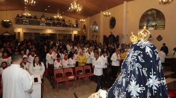 Igreja lotada de fiéis coma imagem da Santa em primeiro plano.