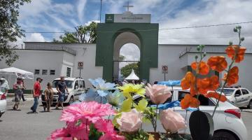fachada de cemitério com vasos de plantas de plástico em primeiro plano. #paratodosverem