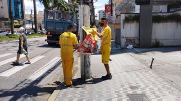 funcionários retiram cartazes de poste #paratodosverem