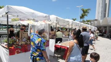 mulher olha barraca de artesanato #paratodosverem