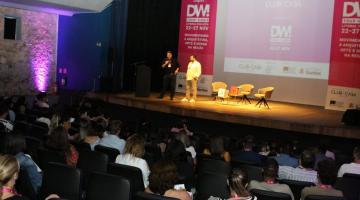 plateia assiste a dois rapazes no palco na abertura do evento #paratodosverem