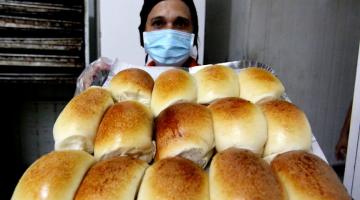 mulher com mascara mostra fornada com pão de cará. #paratodosverem