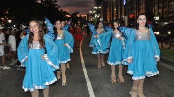patinadoras andam por avenida vestidas com vestidos que têm asas, como borboletas. #paratodosverem 