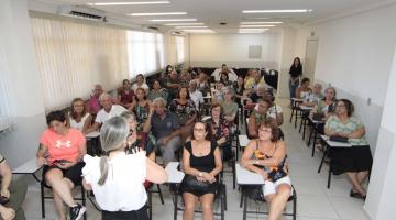 alunos estão sentados em sala de aula atentos a uma mulher que está falando. #paratodosverem