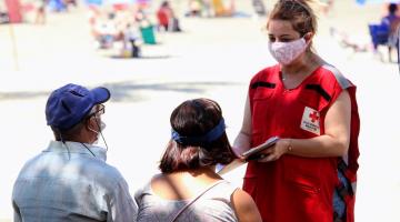 voluntária fala com duas pessoas #paratodosverem