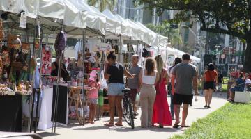barracas de produtos artesanais em praça e pessoas circulando. #paratodosverem