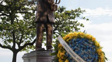 a estátua com coroa de flores à frente. #paratodosverem 
