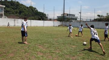 #pracedover No campo do centro esportivo, menino com uniforme de futebol se prepara para chutar bola em direção ao gol