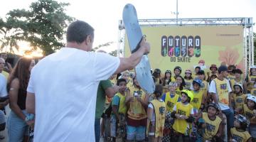 alunos posam para foto diante de painel onde se lê Futuro do Skate. #paratodosverem