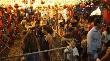 púbico lota praça mauá sob luzes decorativas de natal. Fila para entrar na casinha do papai noel. #paratodosverem 
