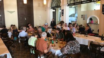 Cerca de 20 pessoa salmoçam em mesas do restaurante Estação Bistrô