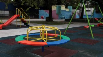 parque infantil com gira-gira em primeiro plano, balancês à direita, escorredor à esquerda e um castelinho ao fundo. #paratodosverem 