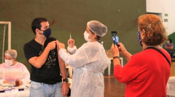 pessoa se vacina enquanto outra fotografa #paratodosverem