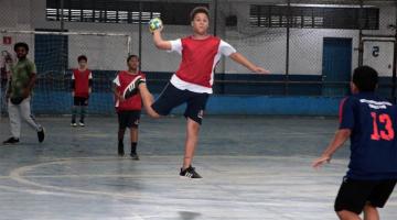 menino está com a bola na mão pronta para lançar. ele está dando um salto, flutuando no ar. #paratodosverem 