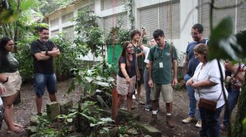 grupode pessoas está em volta de uma composta e uma área verde. #paratodosverem 