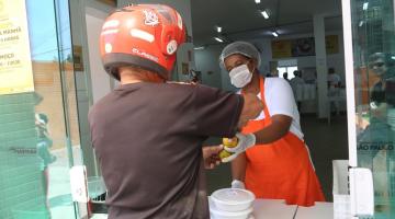 mulher entrega refeição a homem de capacete #paratodosverem 