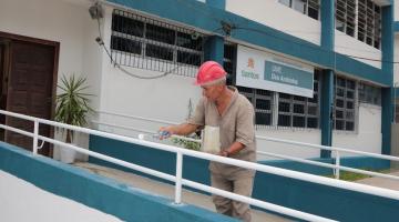 homem está pintando corrimão de rampa de acesso à escola. #paratodosverem