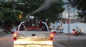 Carro ao centro dispersando inseticida em rua de Santos. #paratodosverem