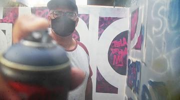 imagem mostra grafiteiro acionando spray de  perto #paratodosverem 