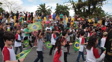 crianças desfilam pela avenida com bandeiras #paratodosverem 