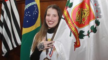 atleta com medalha segurando a bandeira de santos #paratodosverem