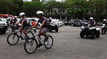 Policiais em bicicletas, quadriciclos e viaturas ao fundo #paratodosverem