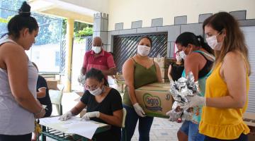 pessoas de máscara recebem as cestas #paratodosverem 