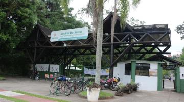 fachada do jardim botânico, com palmeira na entrada e bicicletas estacionadas. #paratodosverem