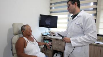 médico segura aparelho e conversa com paciente sentada #pracegover 