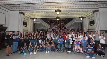 O grande grupo de atletas posa para foto no hall de entrada do paço municipal. #Pracegover