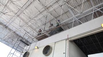 homens estão trabalhando sob estrutura metálica de telhado em andaimes. #paratodosverem 