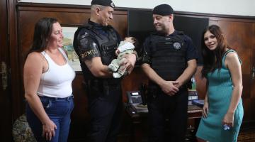 guarda segura bebê ao lado de colega e familiares da criança. #paratodosverem