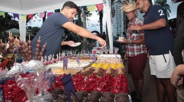 pessoas comprando em barraca de doces #paratodosverem 