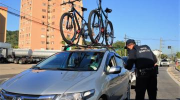 #pracegover Em avenida, guarda aborda motorista de carro com bicicletas na capota