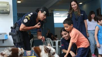 menino brinca com cachorro seguro por guarda municipal #paratodosverem 