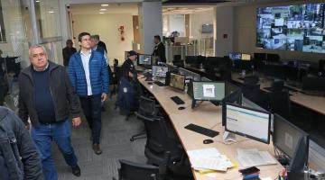 homens observam central com computadores e telas #paratodosverem