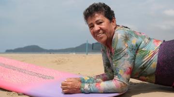 mulher deitada em prancha de surf #paratodosverem