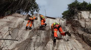 profissionais escalando encosta de morro durante obra #paratodosverem