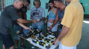 alunos adultos em torno de uma mesa com material elétrico. #paratodosverem 