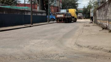 rua asfaltada com desnível em primeiro plano. Ao fundo, um caminhão. #paratodosverem