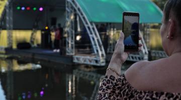 mulher está segurando celular e filmando palco na lagoa da saudade. #paratodosverem 