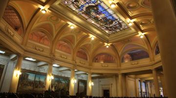 Interior do prédio da antiga bolsa do café, fotografado de baixo para cima. O teto com vitral está em evidência. #Pracegover