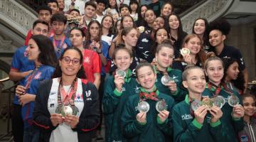 vários atletas exibem medalha em escadaria #paratodosverem