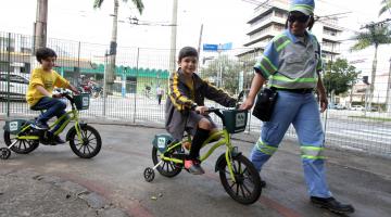 Agente ajuda menino a trafegar de bicicleta na pista #pracegover