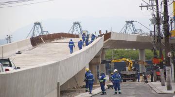 operários caminham sobre e ao lado de viaduto semi pronto #paratodosverem 